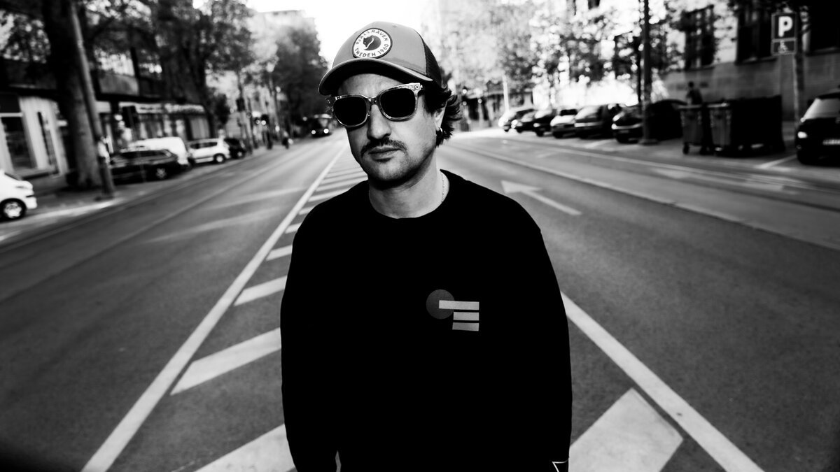 Man in cap, sunglasses and logo sweatshirt standing in empty street