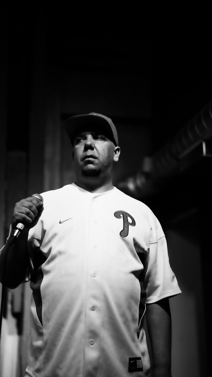 rapper/MC in Phillies jersey and cap holding mic, dramatic portrait