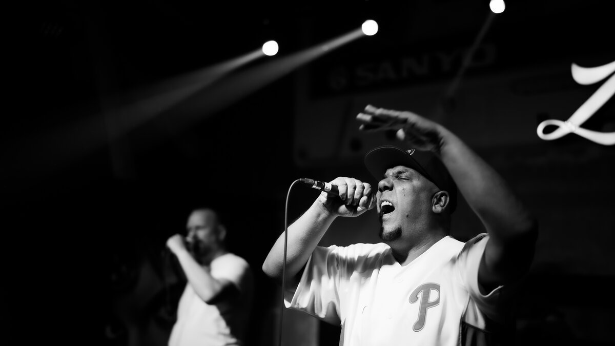 MC mid-performance shouting into mic, stage lights, second performer behind