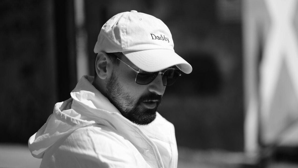 Man in white 'Daddy' cap, sunglasses, white jacket, profile