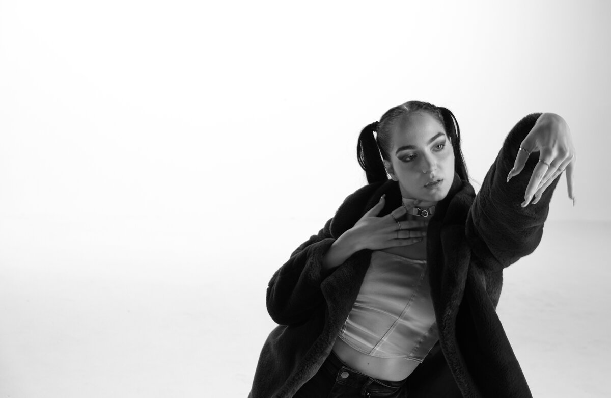 solo female model, dramatic arm pose, oversized coat over corset