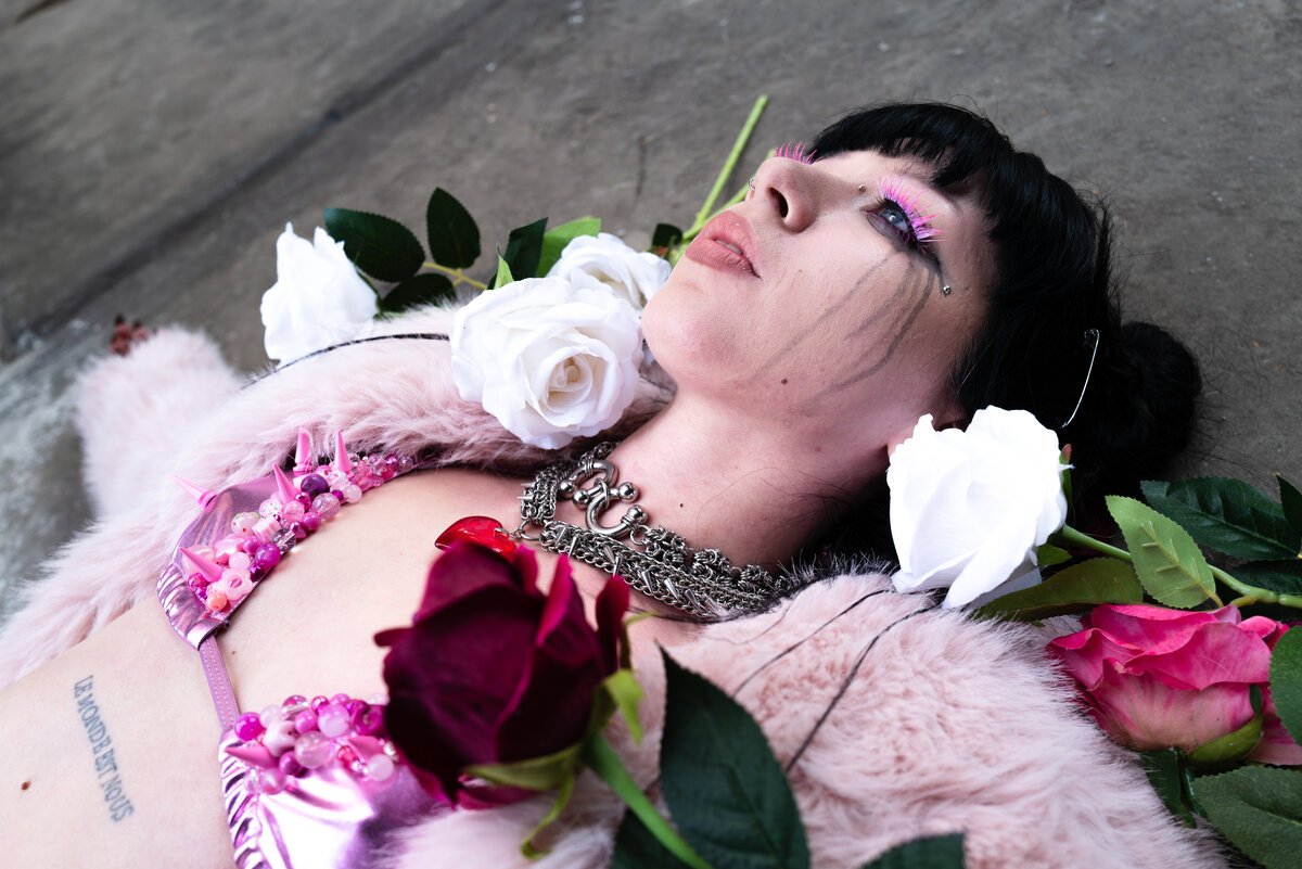 woman lying among white and red roses, pink fur, jewelry, dramatic makeup