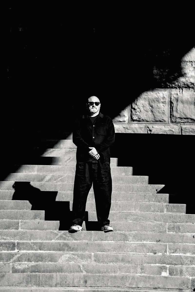 man in sunglasses and black clothing standing on stone steps